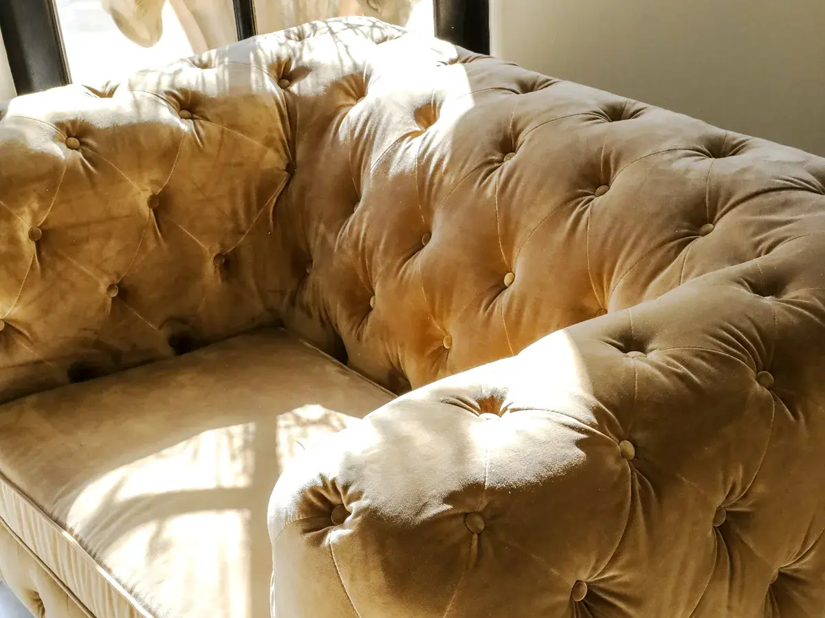 Deep buttoned custom sofa upholstered in champagne velvet for a home in Jubilee Hills, Hyderabad